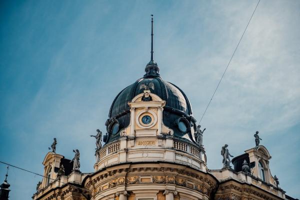 Captivating shot of ornate dome and statues in Ljubljana, Slovenia against a blue sky.
