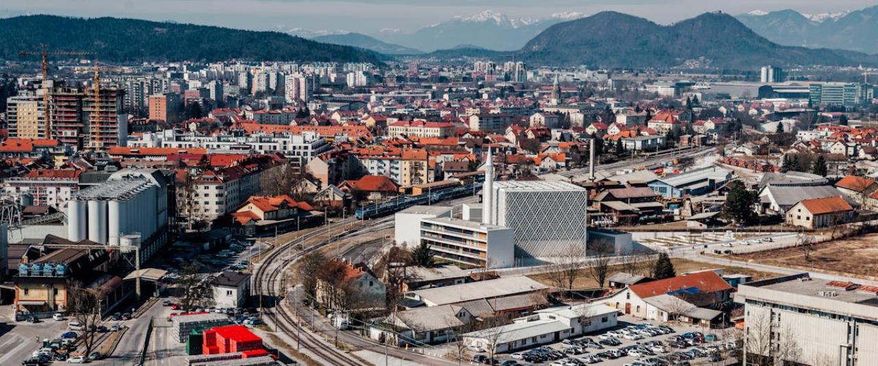 Explore the vibrant cityscape of Ljubljana, Slovenia with this stunning aerial view featuring urban architecture and scenic mountains.