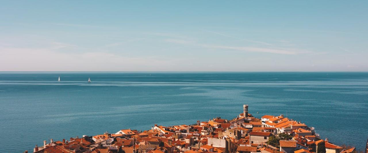 Stunning aerial view of Piran's red rooftops and the Adriatic Sea, showcasing Slovenian coastal architecture.