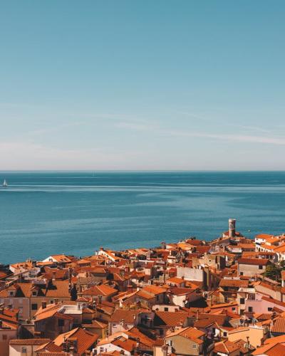 Stunning aerial view of Piran's red rooftops and the Adriatic Sea, showcasing Slovenian coastal architecture.