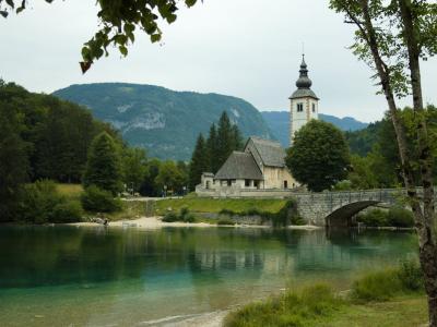 Free Beautiful view of a historic church and bridge in Bohinjska Bistrica, Slovenia, surrounded by nature. Stock Photo