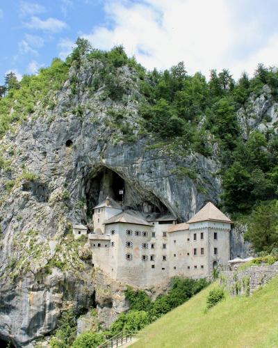 Explore the historic Predjama Castle built into the cliffs of Slovenia, surrounded by lush nature.