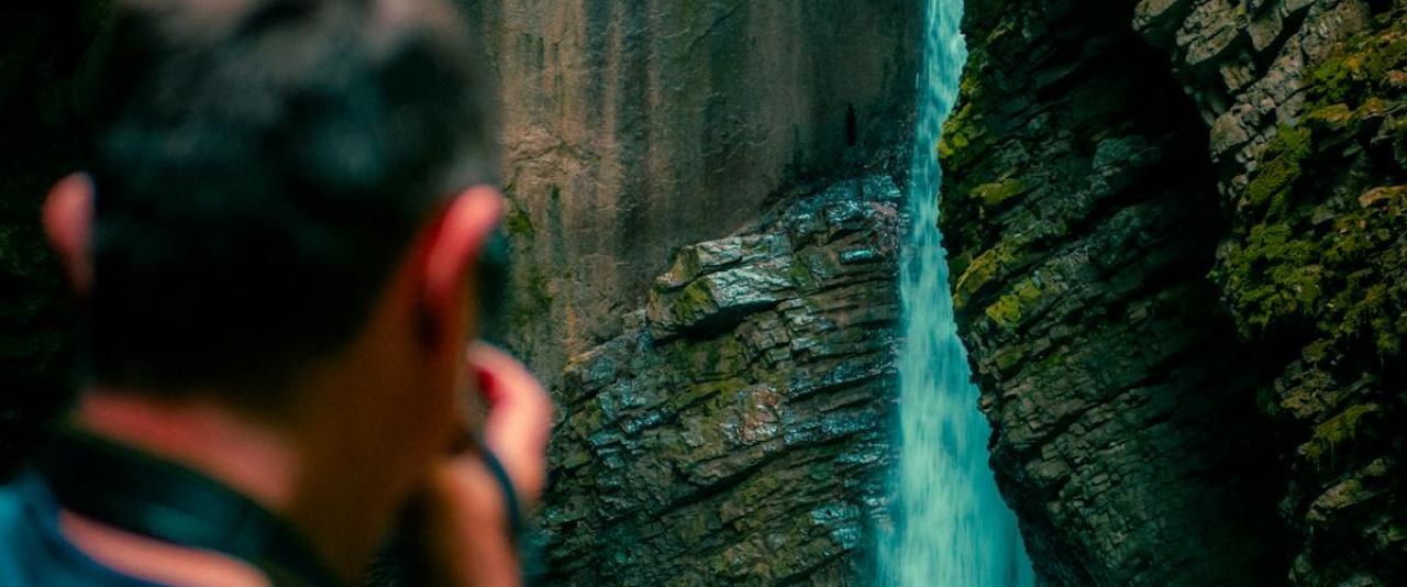 A man photographs the stunning waterfall in the Soča Valley, Slovenia's natural wonder.