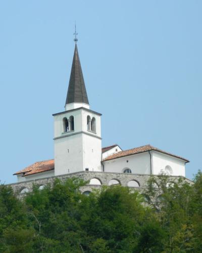 Gothic church tower rising above lush greenery under a clear blue sky in Kobarid, Slovenia.