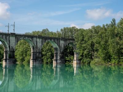 Beautiful arched railway bridge spanning across a serene river in Gorica, Radovljica, Slovenia, surrounded by lush greenery.