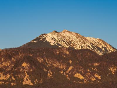 Stunning view of a sunlit mountain in Bled, Slovenia, under a clear blue sky.