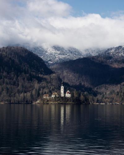 Free Scenic view of Lake Bled with island church surrounded by serene mountains and clouds. Stock Photo