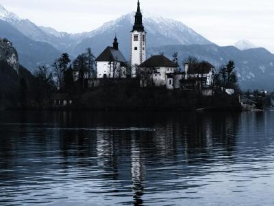 Free Enchanting winter view of Bled Island church reflecting in Lake Bled's tranquil waters. Stock Photo
