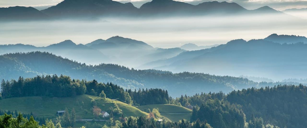 Breathtaking view of Slovenian mountains and valleys under soft morning mist, perfect for travel inspiration.