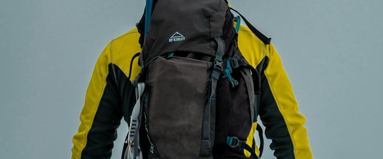 Back view of a backpacker in winter gear hiking in Slovenia's snowy landscape.