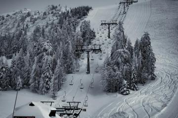 Scenic winter view of a ski resort in Kranj, Slovenia with snow-covered slopes and evergreen trees.