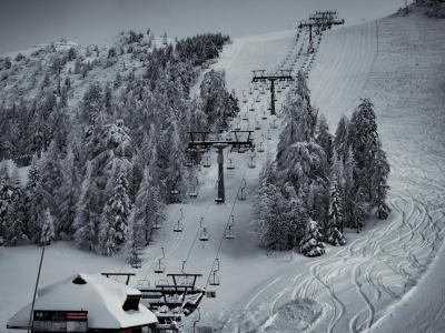 Scenic winter view of a ski resort in Kranj, Slovenia with snow-covered slopes and evergreen trees.