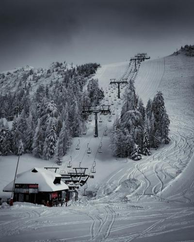Scenic winter view of a ski resort in Kranj, Slovenia with snow-covered slopes and evergreen trees.