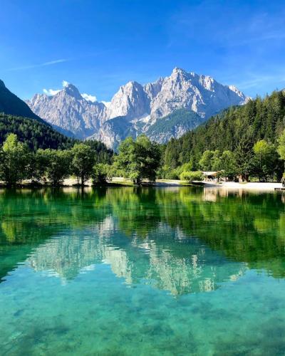 Serene landscape of Lake Jasna reflecting the Julian Alps under a clear blue sky in Slovenia.