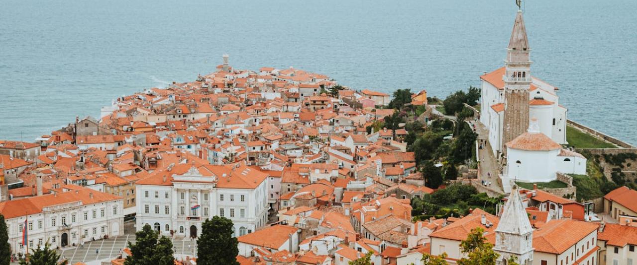 Aerial view highlighting the historic architecture and red rooftops of Piran, Slovenia by the Adriatic Sea.
