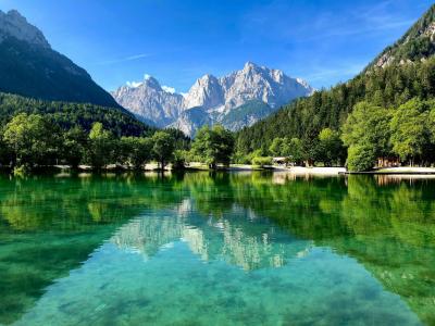 Serene landscape of Lake Jasna reflecting the Julian Alps under a clear blue sky in Slovenia.