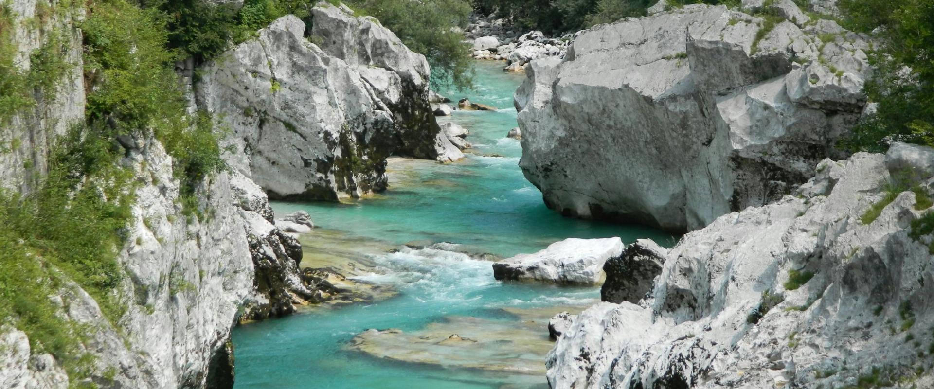 Experience the vibrant turquoise waters of the Soča River amid majestic rocks and lush greenery in Tolmin, Slovenia.