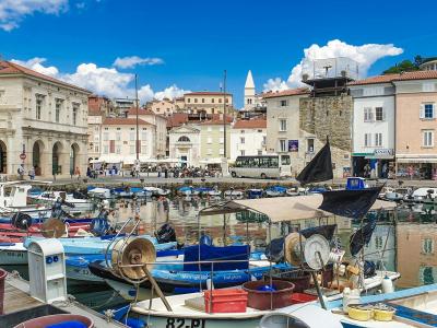 Vibrant harbor in Piran, Slovenia featuring boats and historic architecture under a clear blue sky.