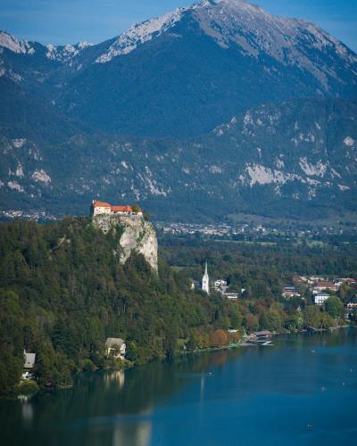 A stunning vertical shot of Bled Castle atop a cliff by Lake Bled with the Julian Alps in Slovenia.