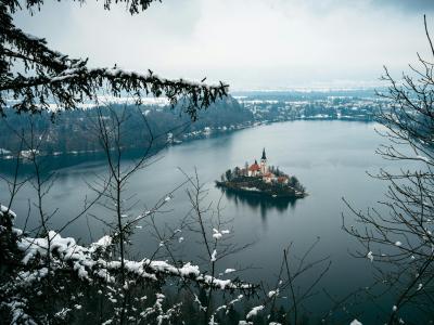 Snowy landscape with a view of Lake Bled and its iconic church on an island.