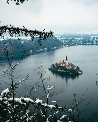 Snowy landscape with a view of Lake Bled and its iconic church on an island.