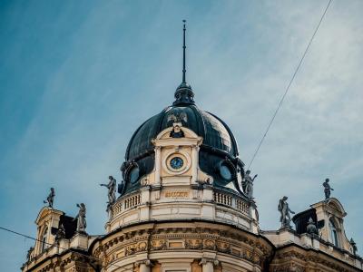 Captivating shot of ornate dome and statues in Ljubljana, Slovenia against a blue sky.