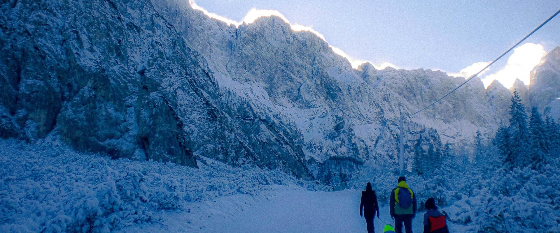 A family enjoying a winter sledding trip in the snowy Slovenian mountains, capturing seasonal joy.