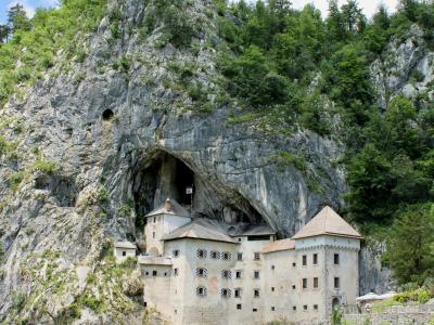 Explore the historic Predjama Castle built into the cliffs of Slovenia, surrounded by lush nature.