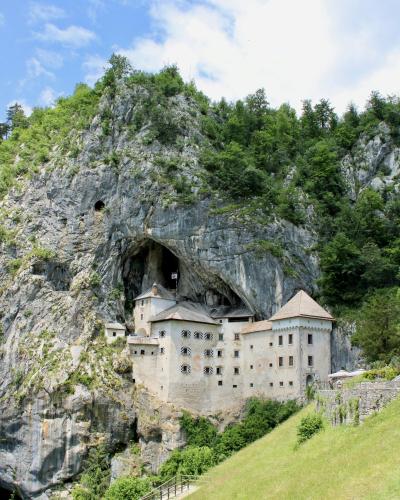 Explore the historic Predjama Castle built into the cliffs of Slovenia, surrounded by lush nature.