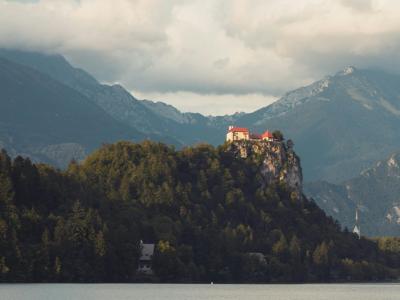 Picturesque Bled Castle overlooking serene Lake Bled, framed by majestic mountains.