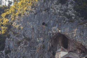 Free Explore the historical Predjama Castle in Slovenia, emerging from a natural cave within a rugged cliff. Stock Photo