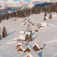 Free Charming wooden cabins blanketed in snow against a majestic mountain backdrop in Slovenia. Stock Photo