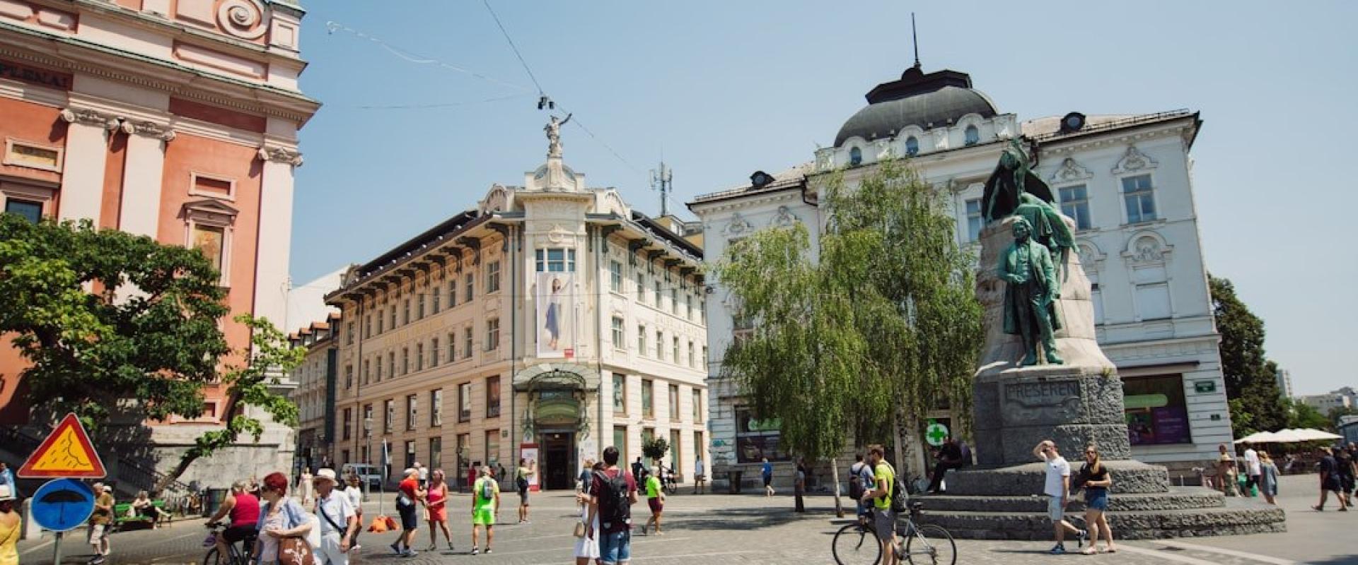 a group of people walking around a statue in a city