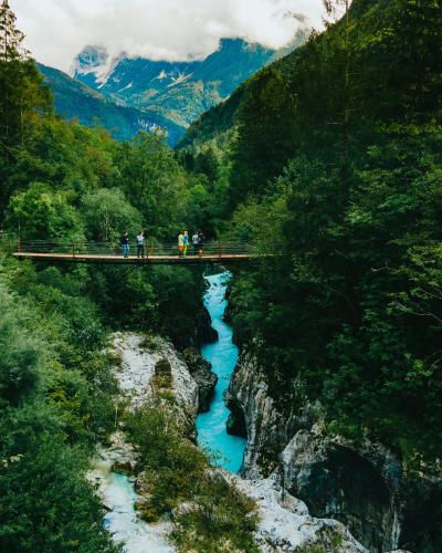 person in green jacket and black pants standing on bridge over river during daytime