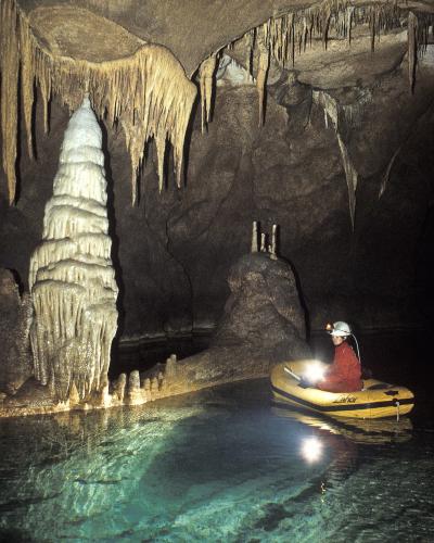 A boat on an underground lake beside a stalagmite in Križna jama