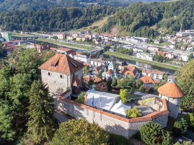 An aerial view of Laško Castle in the foreground, overlooking the town of Laško, the Savinja River, and the historic Laško Brewery complex in the background.