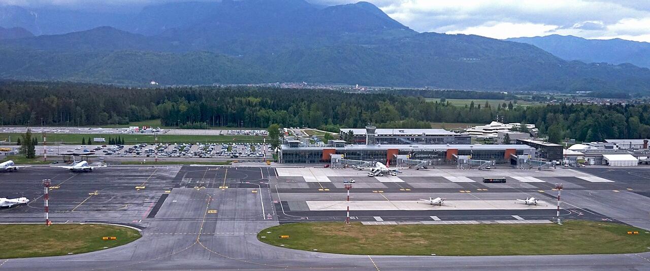 Aerial view of Ljubljana Jože Pučnik Airport terminal and apron with mountains behind